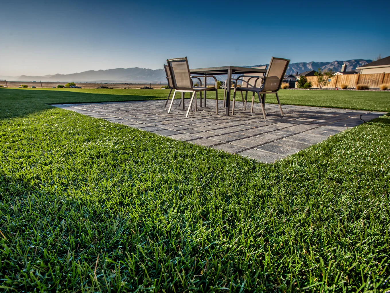 Lush green artificial grass installed around a modern backyard pool overlooking a lake